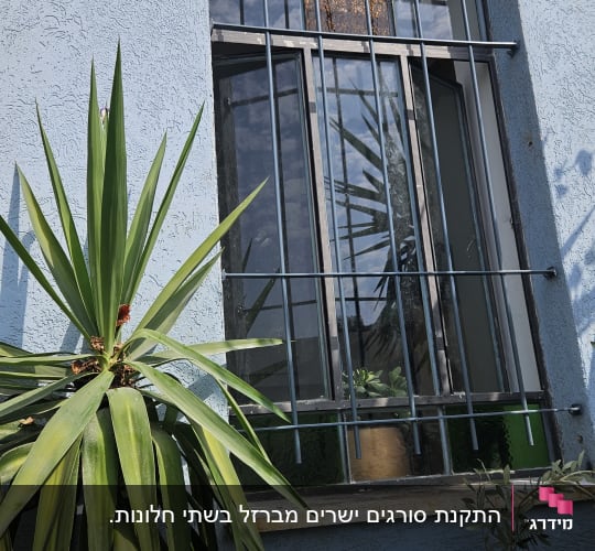חלון עם סורגים מתכתיים על קיר כחול